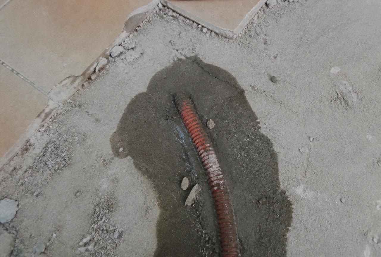Chape ouverte révélant un tube de plancher chauffant humide dans un logement de Melun